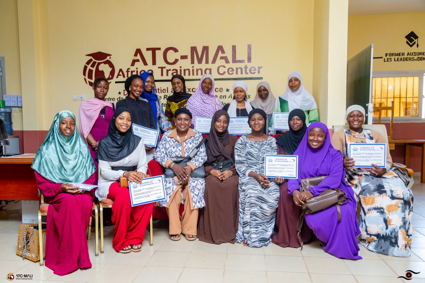 Apprenantes ATC-Mali posant avec leurs attestations devant le logo du centre